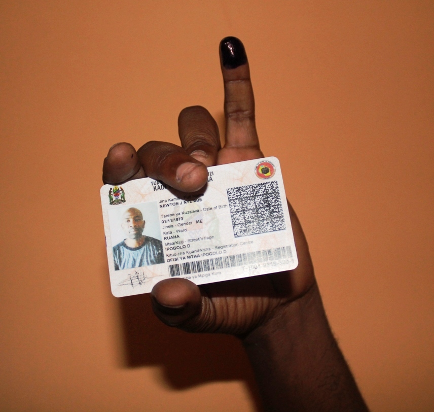 nella foto c'è Newton che mostra la sua tessera elettorale, con il dito colorato con inchiostro indelebile, simbolo che la persona ha già votato